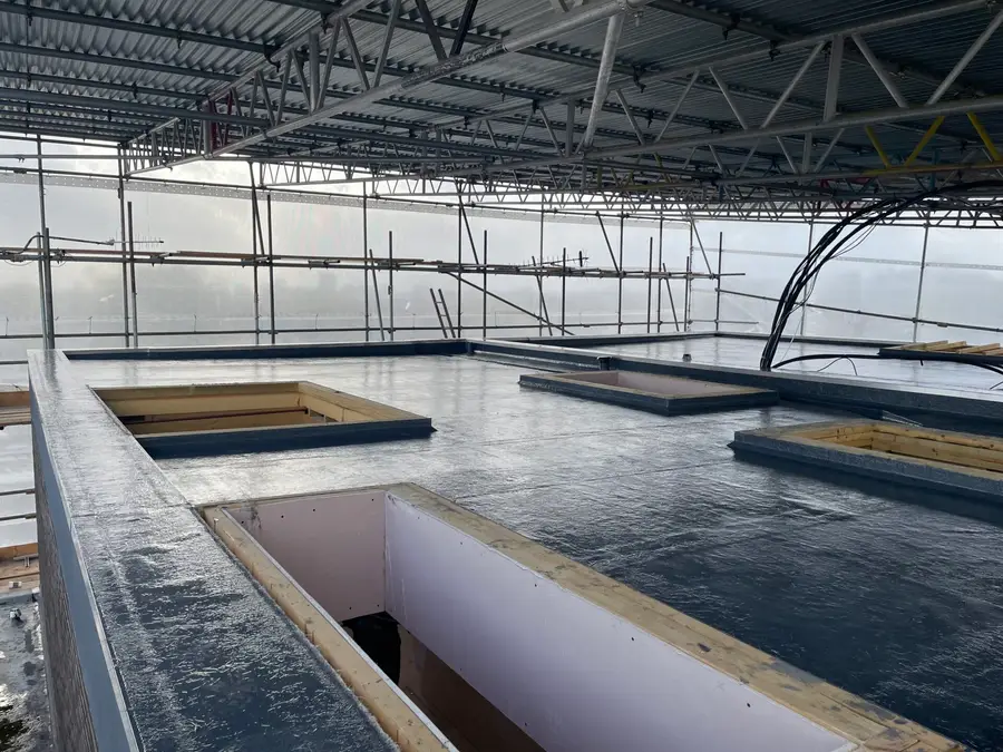 Flat roof under a temporary roof with rooflight openings
