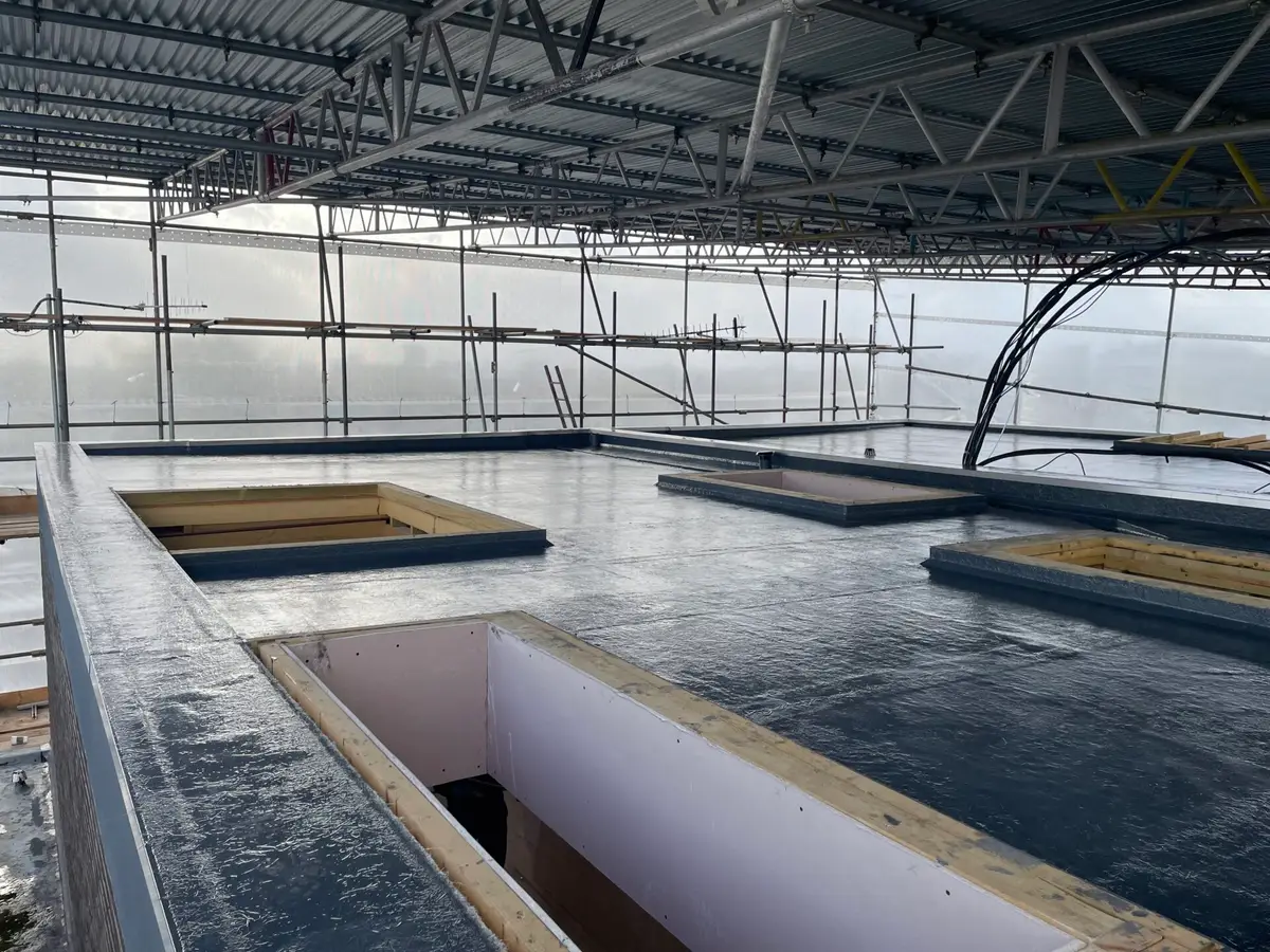 Flat roof with rooflight openings under a temporary roof