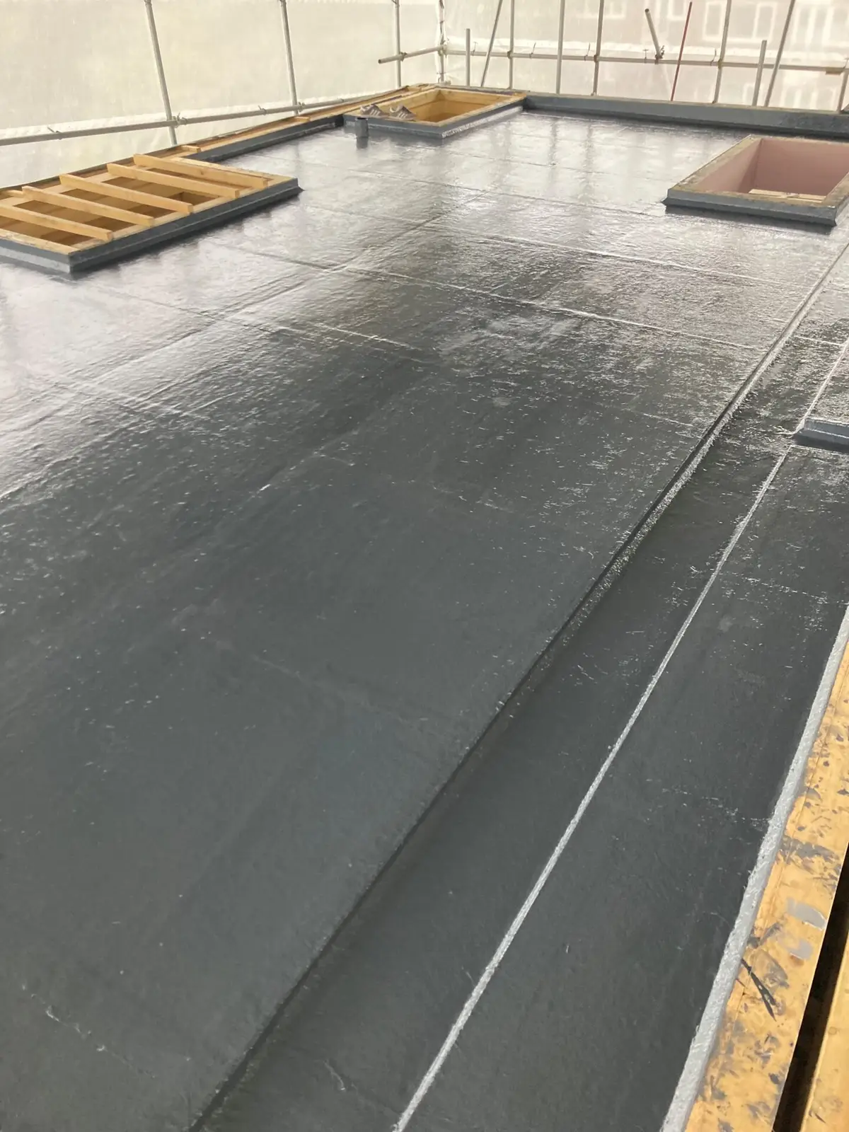 Liquid-applied flat roof under scaffold