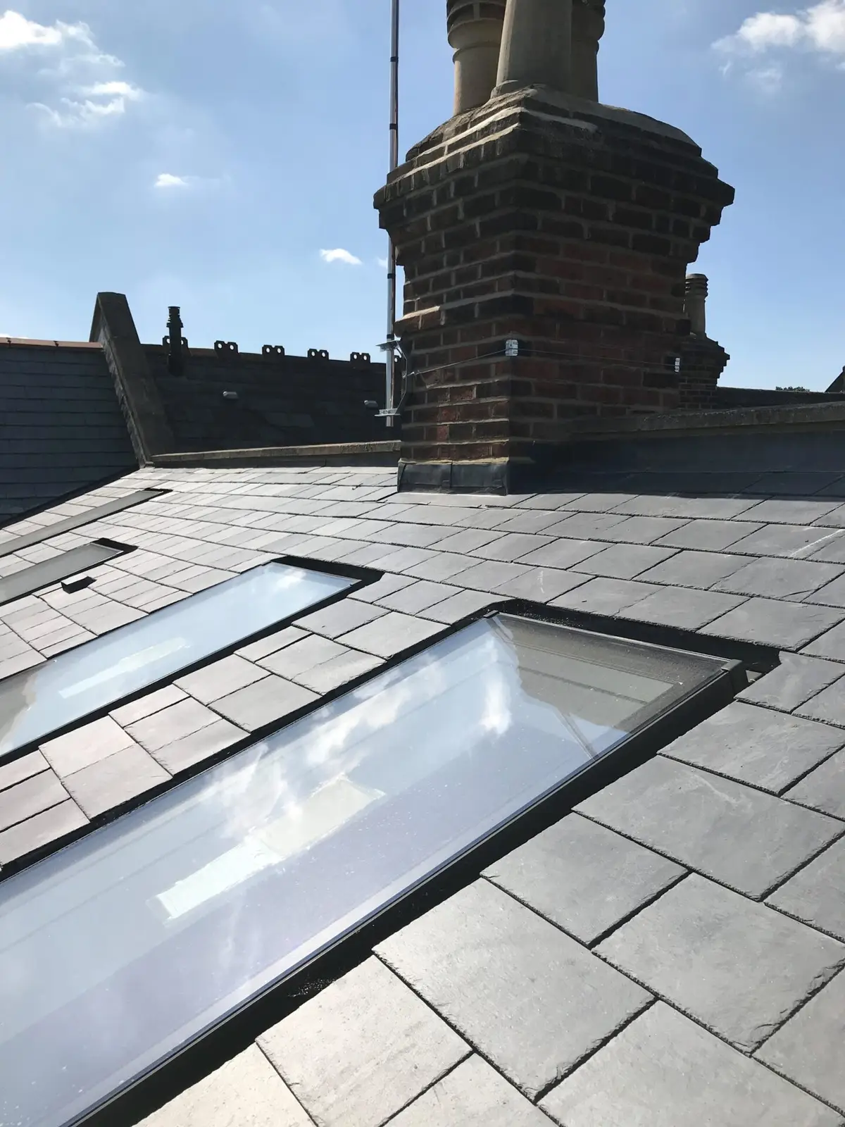 Roof window fitted in a slate roof by a chimney