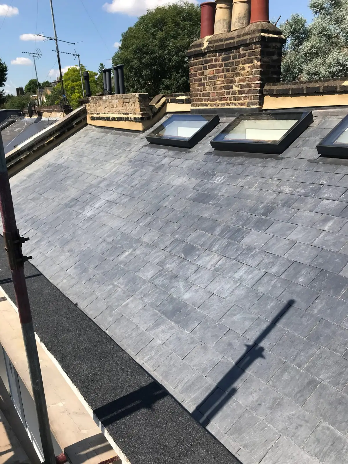 Slate roof with roof windows beside a chimney